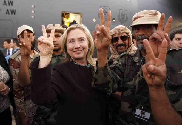 U.S. Secretary of State Hillary Clinton gestures with Libyan soldiers upon her departure from Tripoli in Libya