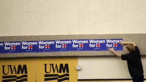 A man puts up "Woman for Hillary" signs before Democratic presidential candidate Hillary Clinton speaks at a meeting in Milwaukee, Wisconsin September 10, 2015. REUTERS/Darren Hauck