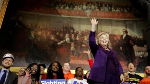Democratic presidential candidate Hillary Clinton, right, stands on stage as she greets people at the start of a rally at Faneuil Hall, Sunday, Nov. 29, 2015, in Boston. The event was held to launch "Hard Hats for Hillary," a coalition created to organize people in industries and labor to support Clinton's agenda. (AP Photo/Steven Senne)