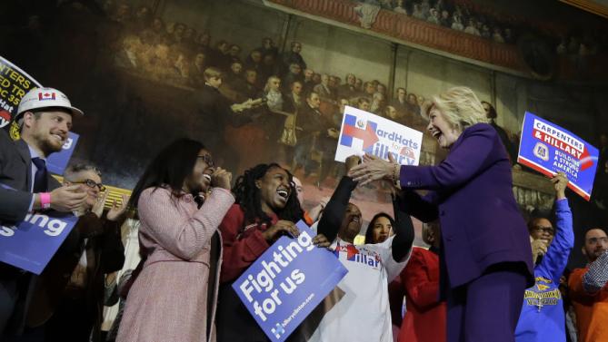 Democratic presidential candidate Hillary Clinton, right, greets people on stage at the start of a rally at Faneuil Hall, Sunday, Nov. 29, 2015, in Boston. The event was held to launch "Hard Hats for Hillary," a coalition created to organize people in industries and labor to support Clinton's agenda. (AP Photo/Steven Senne)