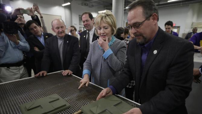 Democratic presidential candidate Hillary Clinton looks at products showing her campaign sign as she tours the Cedar Valley TechWorks, Wednesday, Dec. 9, 2015, in Waterloo, Iowa. (AP Photo/Charlie Neibergall)