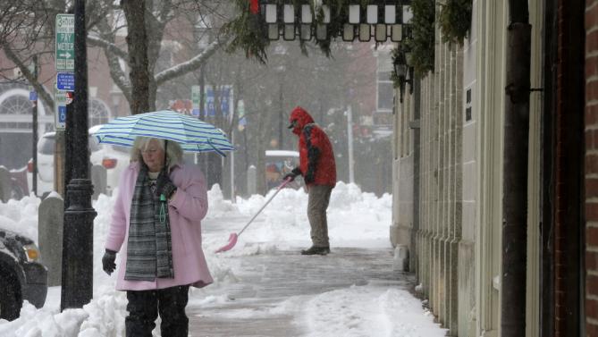 Julie Pugh, of Amesbury, Mass., left, holds an umbrella to shelter herself from snow Tuesday, Dec. 29, 2015 in Portsmouth, N.H. Pugh is visiting Portsmouth to attend a campaign event for Democratic presidential candidate Hillary Clinton. (AP Photo/Steven Senne)