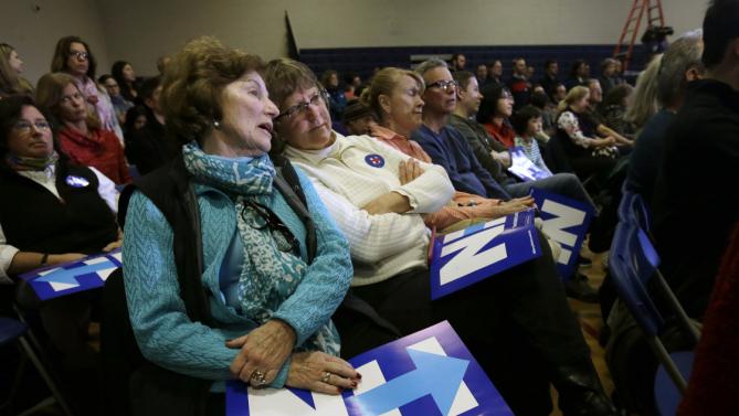 Marilyn Brennan, front, and Kathy Boselli, center, both of Bedford, N.H., hold placards and talk during a town hall style campaign event for Democratic presidential candidate Hillary Clinton, Sunday, Jan. 3, 2016, in Derry, N.H. (AP Photo/Steven Senne)