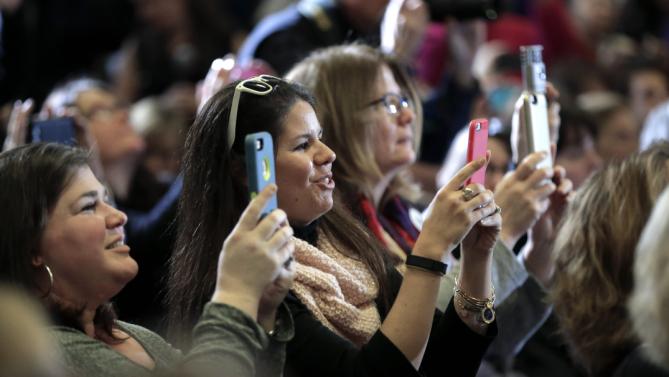 Women in the audience at a town hall campaign event for Democratic presidential candidate Hillary Clinton use their mobile devices during the event Sunday, Jan. 3, 2016, in Derry, N.H. (AP Photo/Steven Senne)