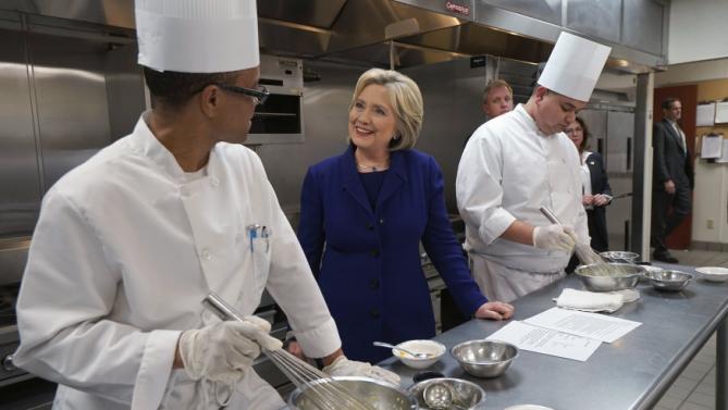 U.S. Democratic presidential candidate Hillary Clinton talks to students Mario Burrell (L) and Gary Brian Gonzalez making mayonnaise while touring the Culinary Academy of Las Vegas in North Las Vegas, Nevada January 6, 2016. REUTERS/Rick Wilking