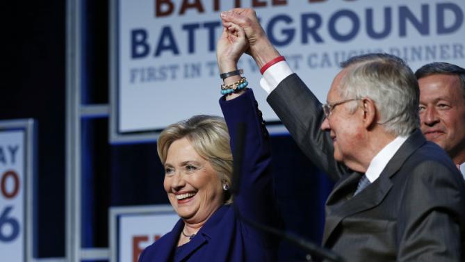 Senate Minority Leader Harry Reid, D-Nev., holds up the hand of Democratic presidential candidate Hillary Clinton on stage at the Battle Born Battleground First in the West Caucus Dinner, Wednesday, Jan. 6, 2016, in Las Vegas. Democratic presidential candidate, former Maryland Gov. Martin O'Malley is at right. (AP Photo/John Locher)
