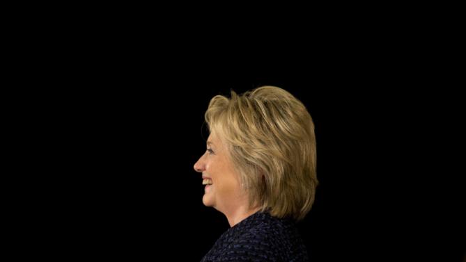 Democratic presidential candidate Hillary Clinton smiles while listening to Transportation Secretary Anthony Foxx speaks during a campaign rally, Monday, Jan. 11, 2016, in Waterloo, Iowa. (AP Photo/Jae C. Hong)