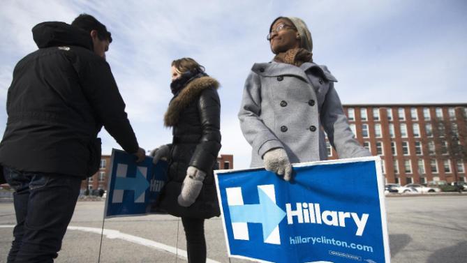 Volunteer Mishara Davis of Atlanta, Ga., right, holds a yard sign outside the Millyard Museum in Manchester, N.H., Tuesday, Jan. 12, 2016, before Chelsea Clinton, daughter of Democratic presidential candidate Hillary Clinton arrived to speak at a campaign stop in support of her mother. (AP Photo/John Minchillo)