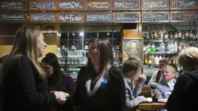 Chelsea Clinton, left, shakes hands with a supporter as customers sit at the bar during a campaign stop for her mother Democratic presidential candidate Hillary Clinton at Portsmouth Brewery, Tuesday, Jan. 12, 2016, in Portsmouth, N.H. (AP Photo/John Minchillo)