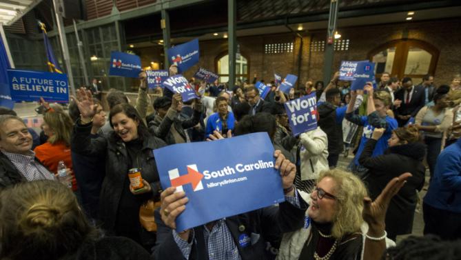 Supporters wave signs, as they dance and sing while they wait for Democratic presidential candidate Hillary Rodham Clinton to arrive at the Jim Clyburn Fish Fry, on Saturday, Jan. 16, 2016, at the Charleston Visitor Center in Charleston, S.C. (AP Photo/Stephen B. Morton)