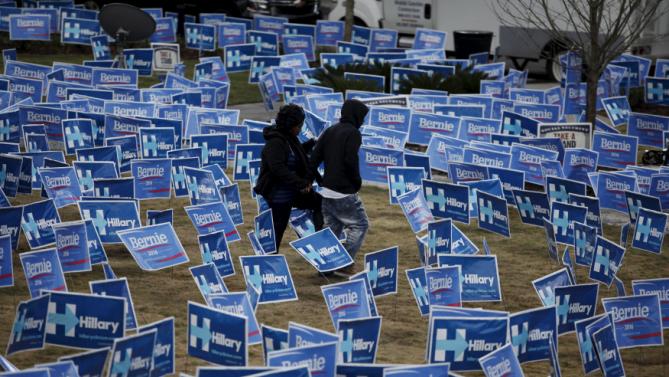 People walk through a maze of political signs for Hillary Clinton and Democratic opponent Bernie Sanders outside the Gaillard Center before the start of the NBC News-YouTube Democratic Debate in Charleston, South Carolina, January 17, 2016. REUTERS/Randall Hill