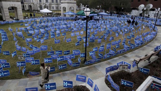 People walk past a maze of political signs for Hillary Clinton and Democratic opponent Bernie Sanders outside the Gaillard Center before the start of the NBC News-YouTube Democratic Debate in Charleston, South Carolina, January 17, 2016. REUTERS/Randall Hill