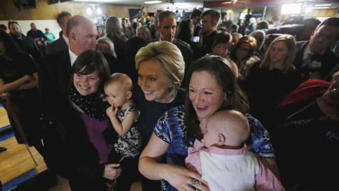 U.S. Democratic presidential candidate Hillary Clinton poses with two supporters and their babies during a campaign stop at the Adel Family Fun Center bowling alley in Adel, Iowa January 27, 2016. REUTERS/Jim Bourg
