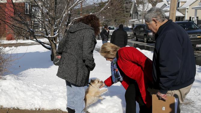 U.S. Democratic presidential candidate Hillary Clinton pets a dog while going to door-to-door to greet voters in a neighborhood in Manchester, New Hampshire February 6, 2016.  REUTERS/Brian Snyder