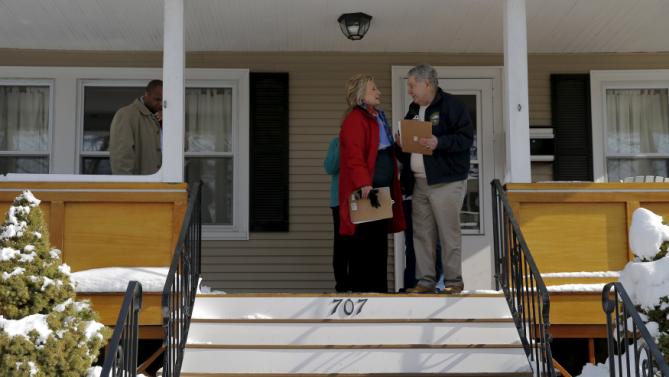 U.S. Democratic presidential candidate Hillary Clinton talks to New Hampshire State Senator Lou D'Allesandro on a porch while going to door-to-door to greet voters in a neighborhood in Manchester, New Hampshire February 6, 2016.  REUTERS/Brian Snyder
