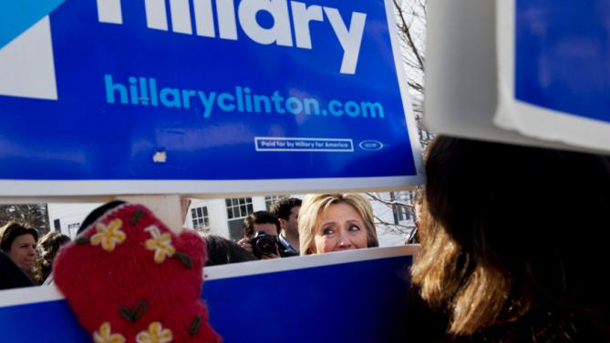 Democratic presidential candidate Hillary Clinton peeks through signs of hers as she greets supporters during a campaign stop in a Manchester, N.H., neighborhood Saturday Feb. 6, 2016. (AP Photo/Jacquelyn Martin)