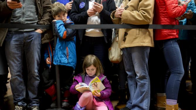 Audrey Clendenning, 6, of Concord, N.H., reads as she and others wait for Democratic presidential candidate Hillary Clinton to arrive in the overflow room of a "Get Out the Vote" event at Rundlett Middle School, in Concord, N.H., Saturday Feb. 6, 2016. (AP Photo/Jacquelyn Martin)