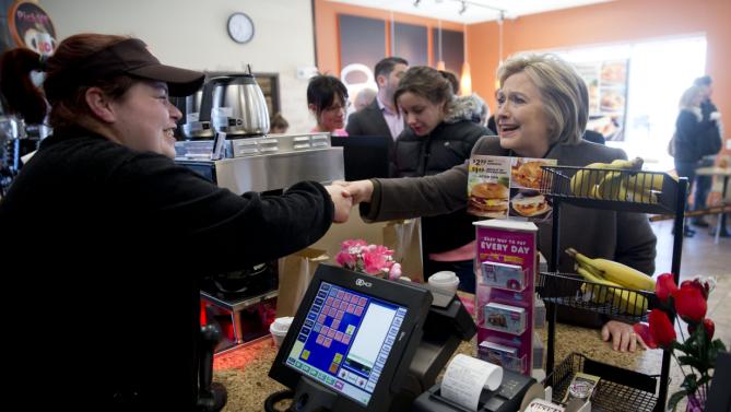 Democratic presidential candidate Hillary Clinton shakes hands with a cashier, Sunday, Feb. 7, 2016, at a Dunkin' Donuts in Manchester, N.H. (AP Photo/Matt Rourke)