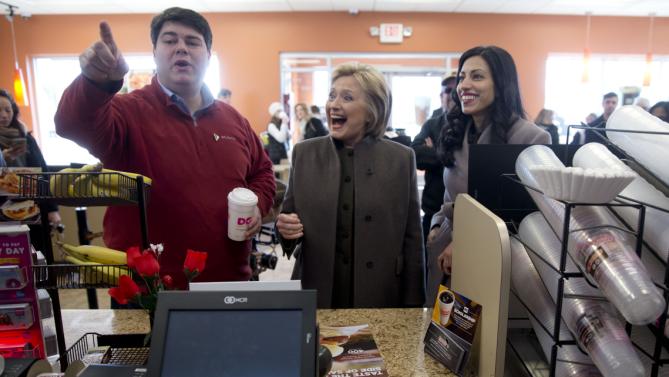 Democratic presidential candidate Hillary Clinton, center, accompanied by Mike Vlacich, New Hampshire state director, Hillary for America, and her aide Huma Abedin look to place their order Sunday, Feb. 7, 2016, at a Dunkin' Donuts in Manchester, N.H. (AP Photo/Matt Rourke)