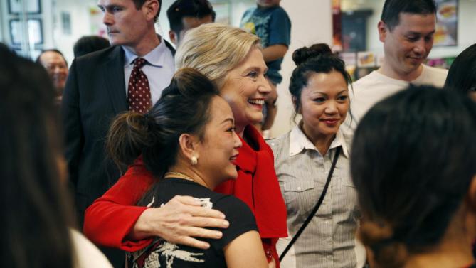 Democratic presidential candidate Hillary Clinton, center in red, visits Lee's Sandwiches during a campaign stop Sunday, Feb. 14, 2016, in Las Vegas. (AP Photo/John Locher)