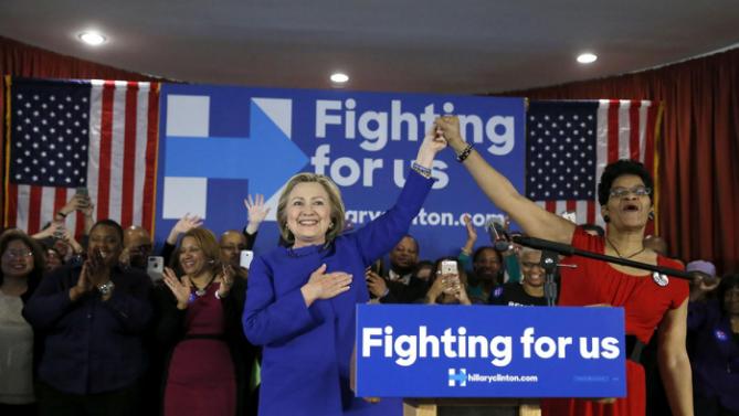 Democratic presidential candidate Hillary Clinton, left, responds to the crowd's applause after an introductory poem by Geneva Reed-Veal, the mother of Sandra Bland, who was found dead in a Texas jail cell, Wednesday, Feb. 17, 2016, during a campaign stop in Chicago. (AP Photo/Charles Rex Arbogast)
