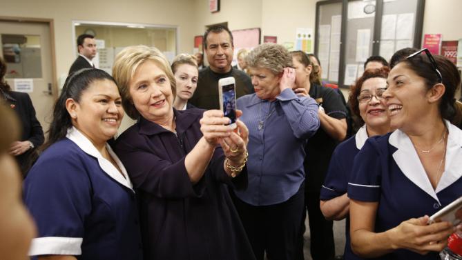 Democratic presidential candidate Hillary Clinton takes a selfie with an employee of Paris Las Vegas during a visit to the hotel and casino Thursday, Feb. 18, 2016, in Las Vegas. (AP Photo/John Locher)