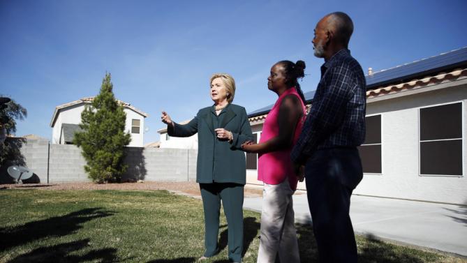Democratic presidential candidate Hillary Clinton, left, visits with Vicki Early, center, and Tyrone Hych at their home Friday, Feb. 19, 2016, in Las Vegas. Early and Hych have solar power at their home. (AP Photo/John Locher)