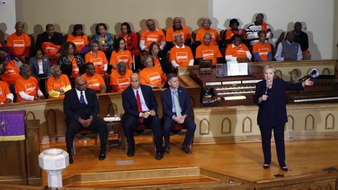 Democratic presidential candidate Hillary Clinton speaks at a campaign event at the Cumberland United Methodist Church in Florence, S.C., Thursday, Feb. 25, 2016. Seated, left to right, are Rev. Anthony Hodge, pastor of the Cumberland United Methodist Church, Sen. Corey Booker, D-N.J., and Dan Gross, president of the Brady Campaign and Center to Prevent Gun Violence. (AP Photo/Gerald Herbert)
