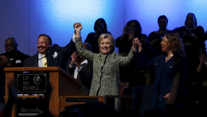 U.S. Democratic presidential candidate Hillary Clinton raises her arms with pastor Bill Adkins (L) after speaking during a church service at the Greater Imani Cathedral of Faith in Memphis, Tennessee, February 28, 2016. REUTERS/Jonathan Ernst