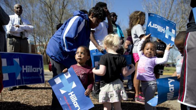 Kids play with campaign signs before Democratic presidential candidate Hillary Clinton arrives to visit a polling place a Southeast Raleigh Magnet High School in Raleigh, N.C., Tuesday, March 15, 2016. (AP Photo/Carolyn Kaster)