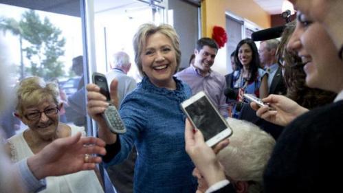 Democratic presidential candidate Hillary Clinton hands a phone back to a woman after speaking to her son as she visits the Dunkin' Donuts in West Palm Beach, Fla., Tuesday, March 15, 2016. Clinton faces Democratic rival Bernie Sanders in primary contests in five states on Tuesday: North Carolina, Florida, Ohio, Missouri and Illinois. (AP Photo/Carolyn Kaster)