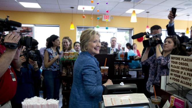 Democratic presidential candidate Hillary Clinton looks to the workers behind the counter as she holds her iced tea during a visit to Dunkin' Donuts in West Palm Beach, Fla., Tuesday, March 15, 2016. Clinton faces Democratic rival Bernie Sanders in primary contests in five states on Tuesday: North Carolina, Florida, Ohio, Missouri and Illinois. (AP Photo/Carolyn Kaster)