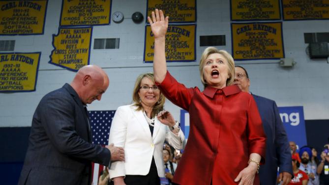 Democratic U.S. presidential candidate Hillary Clinton waves, as former U.S. Representative Gabby Giffords (D-AZ) and her husband Mark Kelly stand nearby, at a campaign rally at Carl Hayden Community High School in Phoenix, Arizona March 21, 2016. REUTERS/Mario Anzuoni