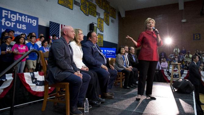 Democratic presidential candidate Hillary Clinton speaks at a campaign event at Carl Hayden Community High School in Phoenix, Monday, March 21, 2016. On stage with Clinton from left are Former Rep. Gabrielle Giffords, and her husband astronaut Mark Kelly, Governor of the Gila River Indian Community Stephen Roe Lewis, labor leader Dolores Huerta, and Rep. Ruben Gallego, D-Ariz., and Labor Secretary Thomas Perez. (AP Photo/Carolyn Kaster)