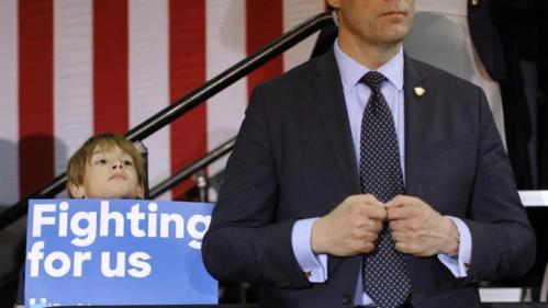 A child holds a campaign sign alongside a member of the U.S. Secret Service as Democratic presidential candidate Hillary Clinton speaks at the Mary Ryan Boys and Girls Club in Milwaukee, Wis., Monday, March 28, 2016. (AP Photo/Patrick Semansky)