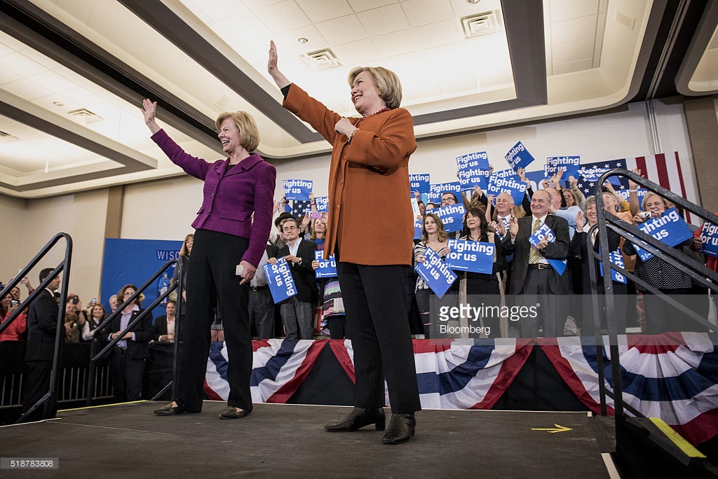 Hillary Clinton, former Secretary of State and 2016 Democratic presidential candidate, right, and Senator Tammy Baldwin, a Democrat from Wisconsin, wave during a campaign event in Eau Claire, Wisconsin, U.S., on Saturday, April 2, 2016. Clinton used Donald Trump's remarks about punishing women who have abortions if the procedure were outlawed to level a double-barreled attack on the Republican front-runner as well as her Democratic rival, Bernie Sanders. Photographer: Christopher Dilts/Bloomberg *** Local Caption *** Hillary Clinton; Tammy Baldwin